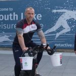 One man on a spin bike and one man standing outside