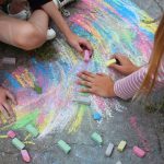 two teens using chalk on pavement