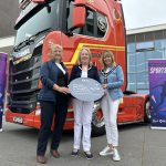 3 females standing in front of a Manfreight Limited lorry cab.