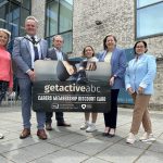 Six people standing in front of the South Lake Leisure Centre holding a card to promote the new getactiveabc carers membership card.