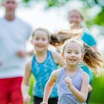 Two adults and two children running outside