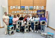 A group of people standing wth boxes containing air fryers and slow cookers, with a banner for Multiply