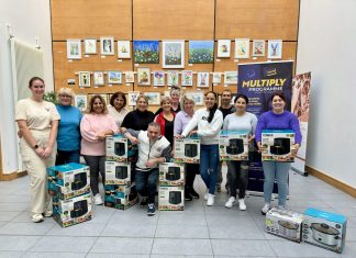 A group of people standing wth boxes containing air fryers and slow cookers, with a banner for Multiply