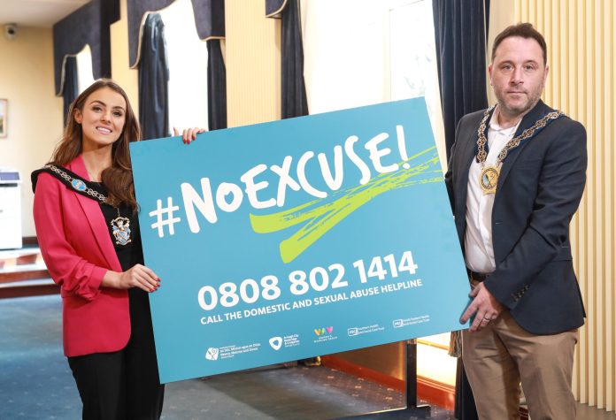 Lord Mayor and Chairperson stand holding a board with the words No Excuse and the helpline phone number 0808 802 1414