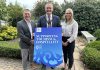 Three adults - two males and one female are holding a prop to promote the ABC Council's Sustainable Business Programme for tourism businesses.