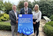 Three adults - two males and one female are holding a prop to promote the ABC Council's Sustainable Business Programme for tourism businesses.