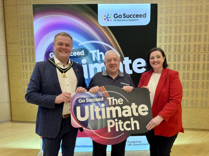 Three people holding a sign that says Ultimate Pitch, with a backdrop for Go Succeed Business Support