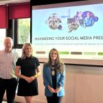 Three people standing in front of a projection screen saying 'Maximising your social media presence'.