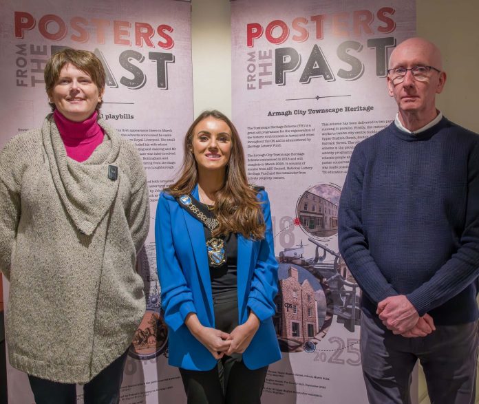 The Lord Mayor Councillor Sarah Duffy is pictured with a female and male in front of pop up banners saying Posters from the Past'. They are pictured together to promote the Posters from the Past Exhibition at Armagh County Museum.