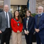 Four people standing outside a building, one of which is Lord Mayor wearing their chain.