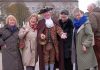 A group of people standing beside a man dressed in Georgian clothes.