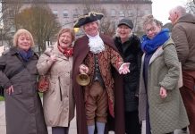 A group of people standing beside a man dressed in Georgian clothes.