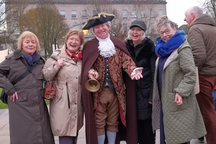 A group of people standing beside a man dressed in Georgian clothes.