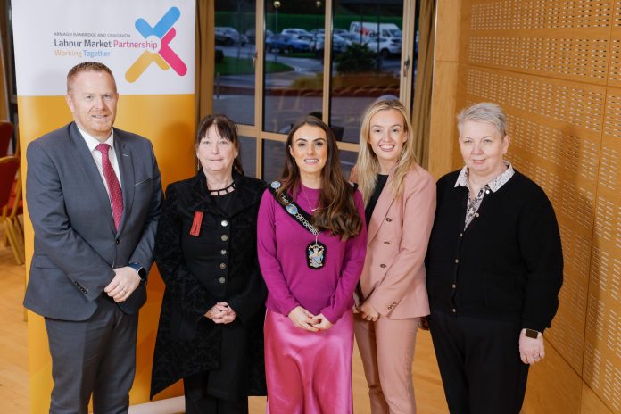 5 people standing in a row, with Lord Mayor in the middle. Behind them is a stand saying Labour Market Partnership.