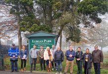 A number of people standing in a line in front of a sign that says Lurgan Park.