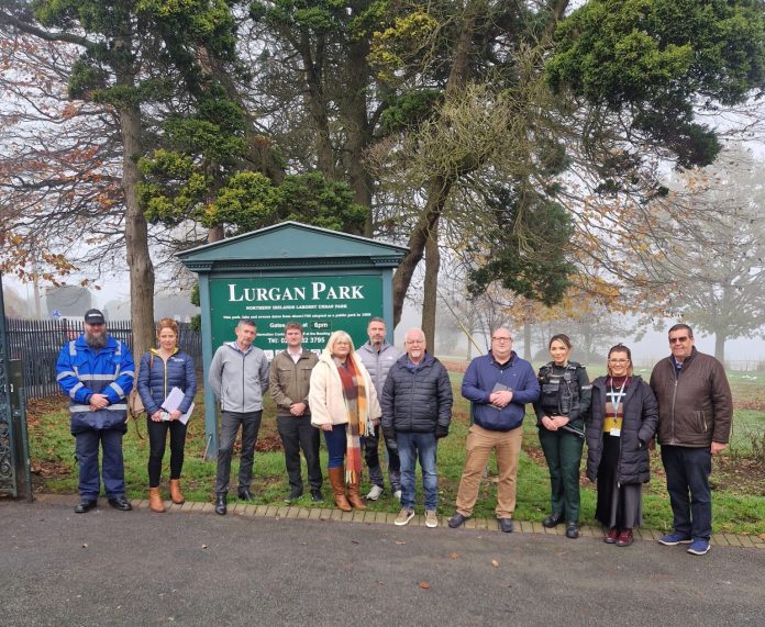 A number of people standing in a line in front of a sign that says Lurgan Park.