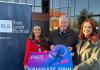 Three people posing with a banner to promote the 2025 senior sports awards.