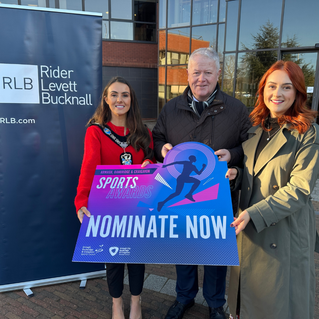 Three people posing with a banner to promote the 2025 senior sports awards.