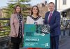 Three people standing together with the person in the middle holding a sign to promote the employability and skills conference.